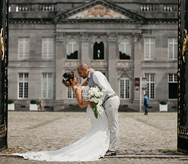 Portrait de couple de mariés en lumière naturelle le jour de leur mariage dans un portail à l'entrée du chateau de Seneffe